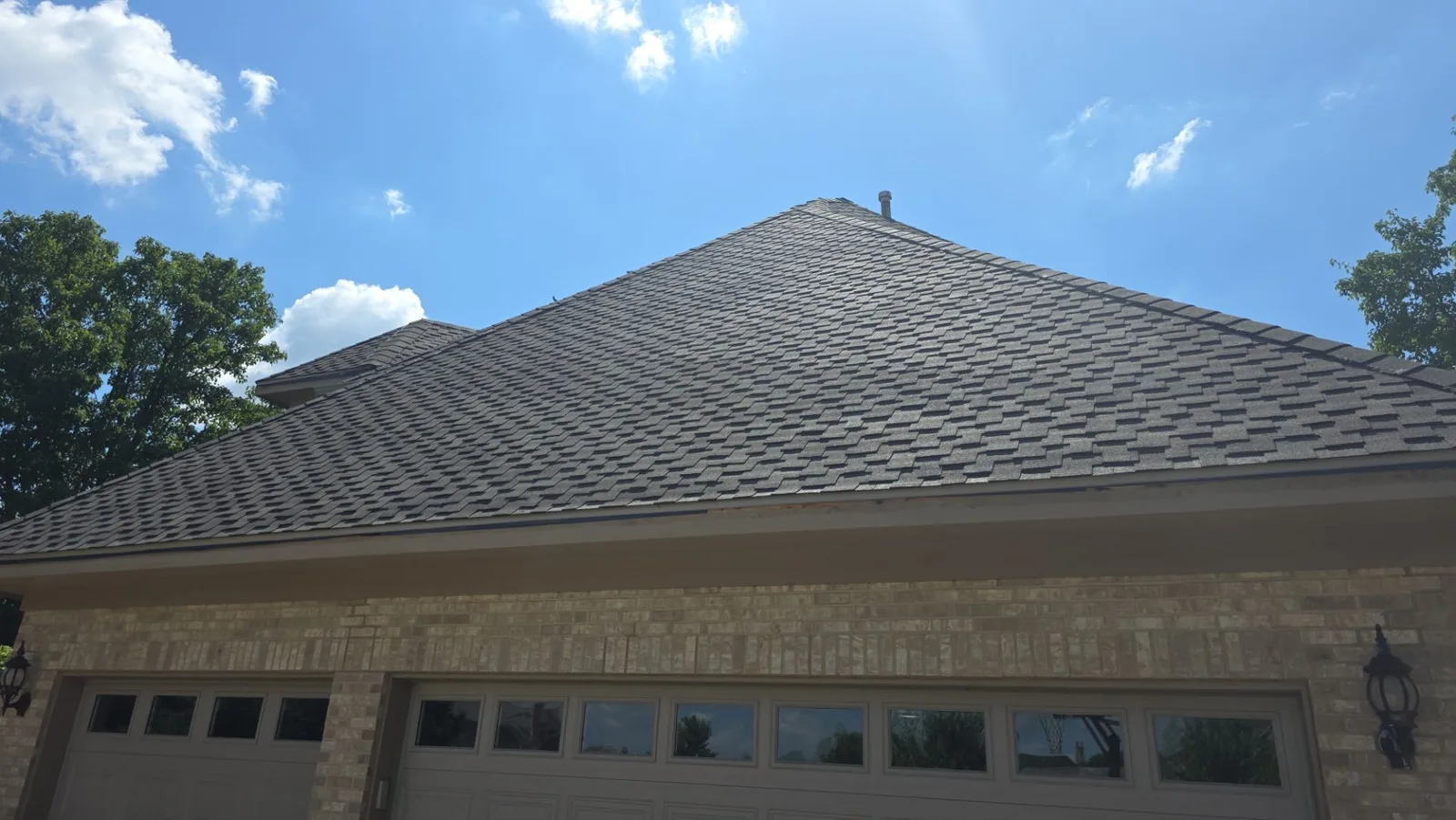 Completed asphalt shingle roof replacement under blue sky by RG Roofing & Exteriors